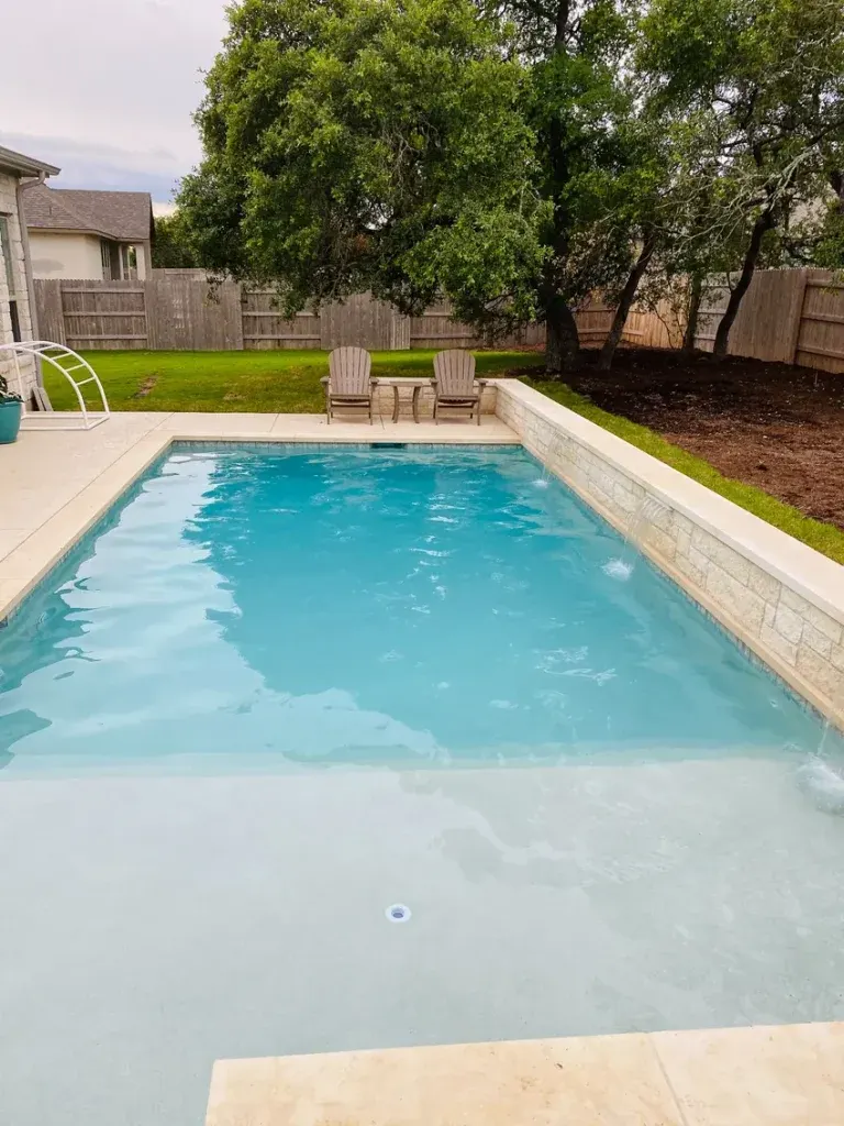 Turquoise backyard swimming pool with curved entry steps