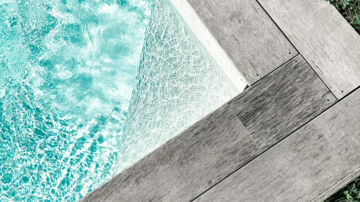 Residential backyard swimming pool with trees and outdoor seating