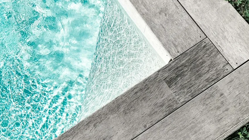 Residential backyard swimming pool with trees and outdoor seating